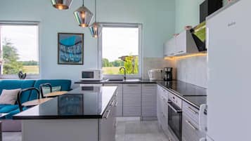 Una cocina moderna con una isla central, electrodomésticos de acero inoxidable y vistas al exterior.