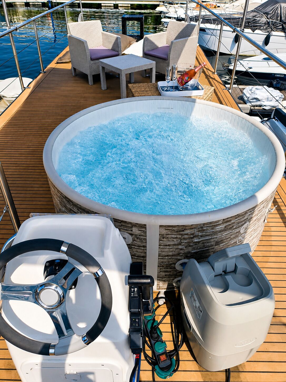 A hot tub on a boat deck with a steering wheel, control panel, and power outlet.