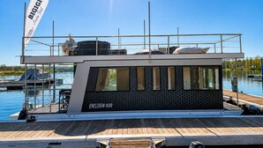 En moderne båd med overdækket dæk, navnet 'BIGIGIO', og modellen 'EXCLUSIV 930'.