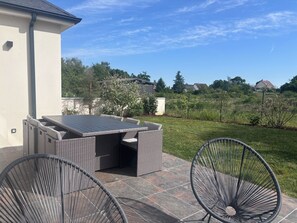 An outdoor patio with a table and chairs, a grassy lawn, and a view of a residential area. - Stopover at the gates of Amboise (Chargé)