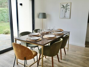 A dining area with a table set for six, surrounded by chairs, a lamp, and a framed botanical illustration on the wall. - Stopover at the gates of Amboise (Chargé)