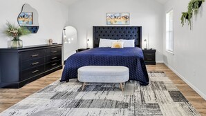 Una camera da letto con un letto grande, una cassettiera, uno specchio e due piante fissate alla parete.
