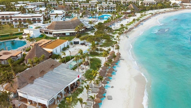 An aerial view of a resort with beachfront accommodations, a swimming pool, and a beach with umbrellas. - Akumal Alma | Walk to Beach | Sea View Roof Pools (Akumal)