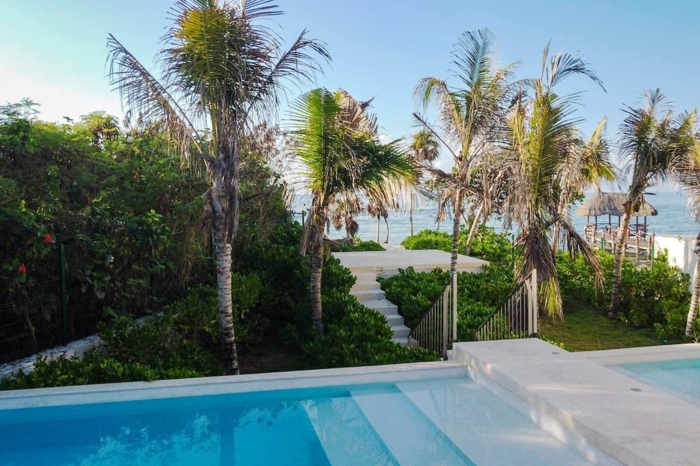 Zwembad met uitzicht op zee, omringd door palmbomen en een houten terras.