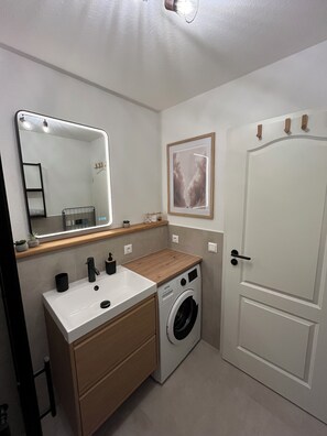 A compact bathroom with a sink, mirror, and washing machine. - Feel good at Stadtpark GZ - central & stylish (Günzburg)