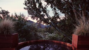 Une terrasse en bois avec une piscine circulaire, entourée de jardinières en bois où sont plantées des graminées.