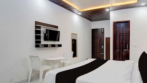 A hotel room with a bed, a small table, a chair, a TV, and a wardrobe. - Hotel Brothers  (Dera Bassi)
