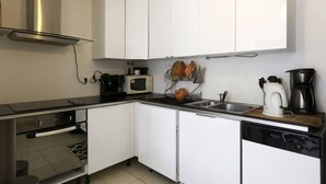 A compact kitchen with white cabinets, a microwave, a coffee maker, and a dishwasher. - Town house 1000 metres from Paris (Saint-Ouen-sur-Seine)