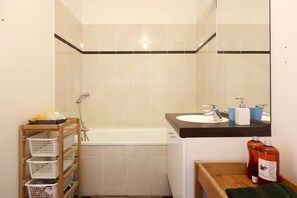 Ein Badezimmer mit einer Badewanne, einem Waschbecken mit Spiegel und einem Ablagefach für Toilettenartikel.