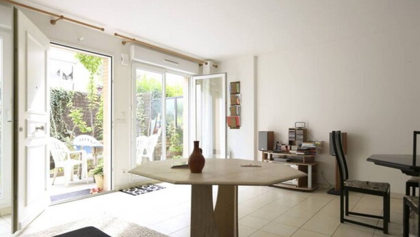 A room with a large table, a chair, a bookshelf, and a door leading to an outdoor area. - Town house 1000 metres from Paris (Saint-Ouen-sur-Seine)
