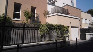 A modern apartment building with a brick facade, a balcony, and a gated entrance. - Town house 1000 metres from Paris (Saint-Ouen-sur-Seine)