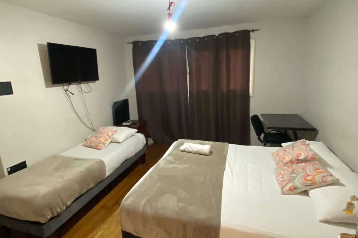 Een hotelkamer met twee enkele bedden, een bureau, een flatscreen-tv en een gordijn.