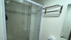 Une salle de bain comprenant des toilettes, un espace douche, un lavabo et un sèche-mains.