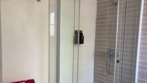 Une salle de bain avec une douche en verre, des toilettes et une petite plante en pot.