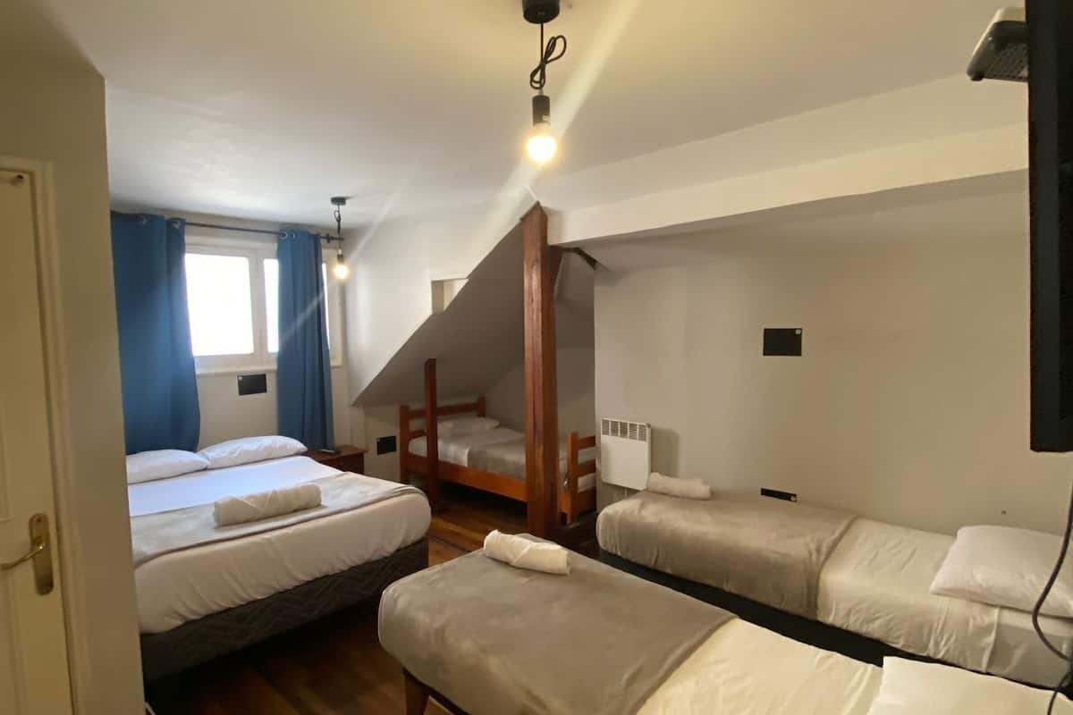 Een slaapzaal met stapelbedden, een houten plafond en een raam met gordijnen.
