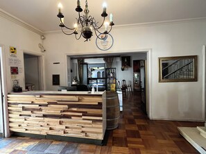 A reception area with a wooden reception desk, a chandelier, and a sign above the desk. - BbCasitaBlue Hotel (Santiago)