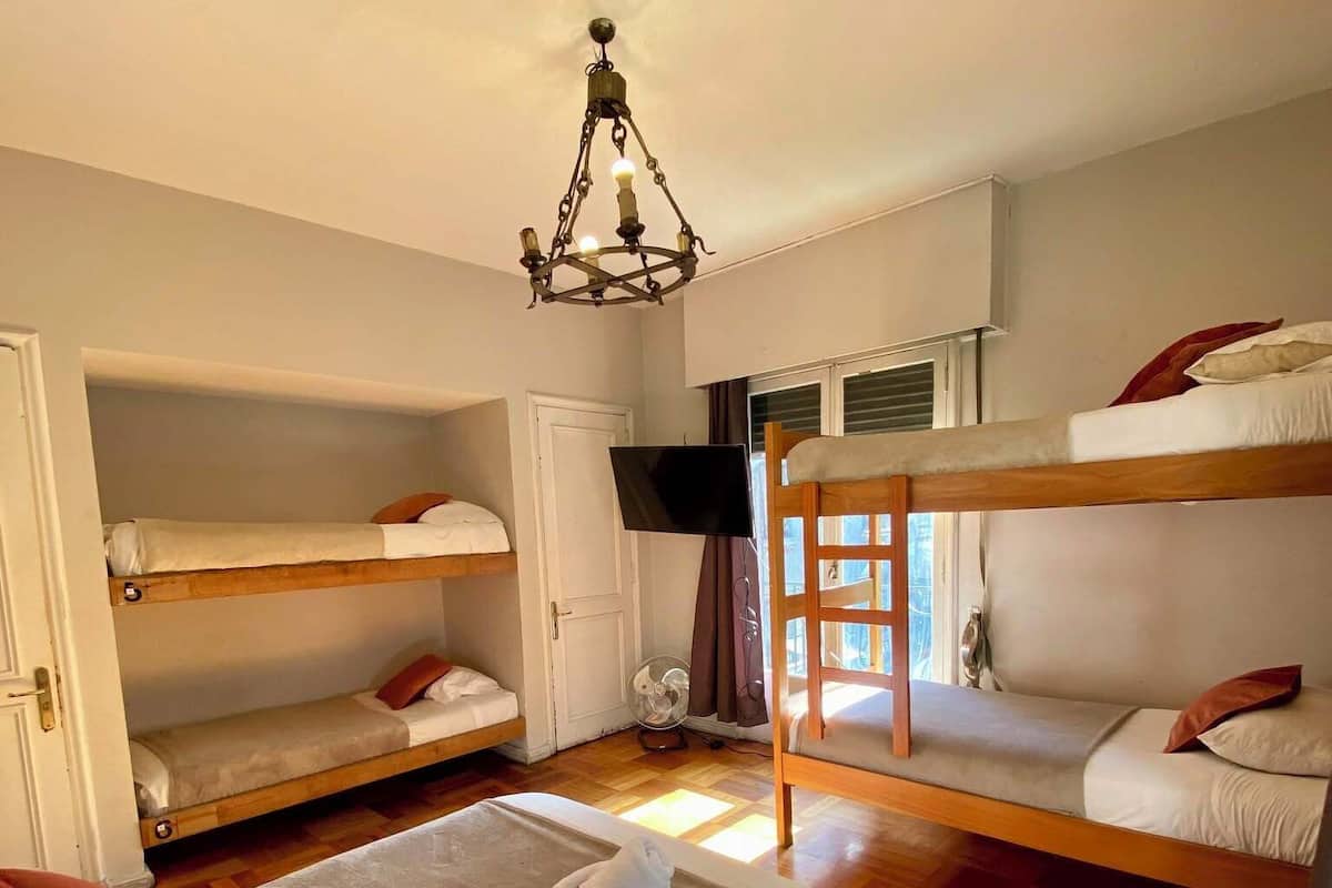 Een kamer met stapelbedden, een flatscreen-tv, een plafondventilator en een kroonluchter.