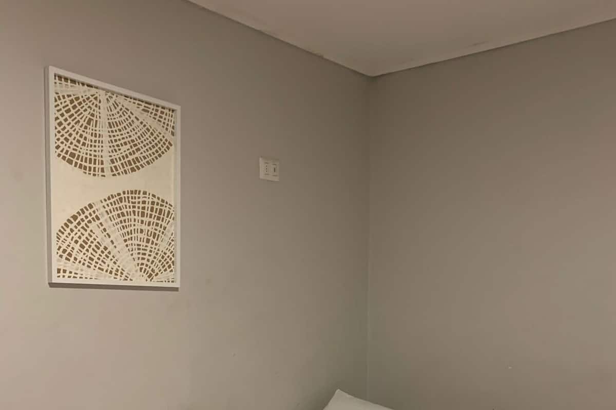 Een kamer met een bed, een bedlaken met bloemenprint, een opgerolde handdoek en een wanddecoratie.