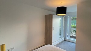 Un dormitorio con cama, armario y ventana que da a un balcón.