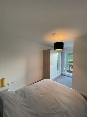 Ein Schlafzimmer mit einem Bett, einem Kleiderschrank und einem Fenster zum Balkon.