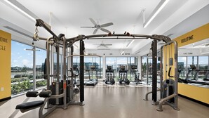 A modern gym with ceiling fans, various exercise equipment, and large windows offering city views. - Lux Studio ,Pool, Near St. Davids Hospital (Jarrell)