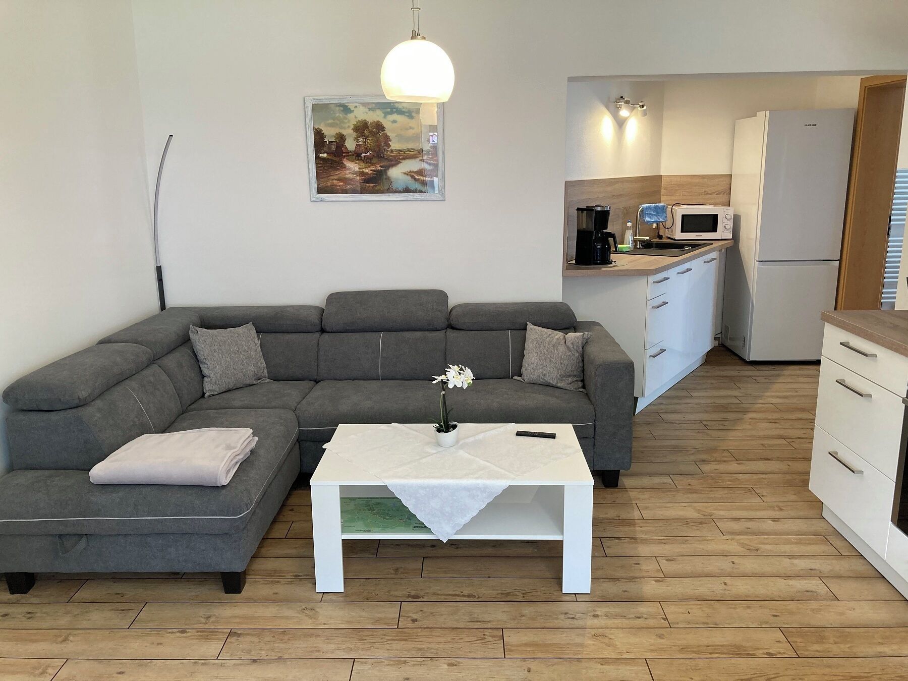 Ein modernes Wohnzimmer mit einem grauen Modulsofa, einem weißen Couchtisch und einem Bild an der Wand.