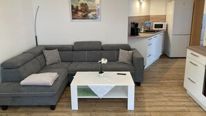 Uma sala de estar moderna com um sofá seccional cinza, uma mesa de centro branca e um quadro na parede.