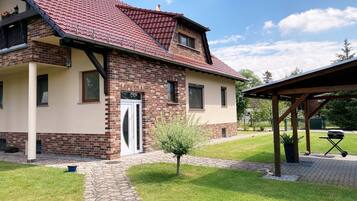 Ein zweistöckiges Haus mit rotem Ziegeldach, einer Ziegelaußenwand und einem kleinen Vorgarten mit einem Weg zum Eingang.