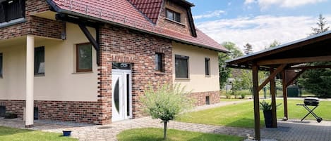 A two-story house with a red-tiled roof, a brick facade, and a small front yard with a pathway leading to the entrance.