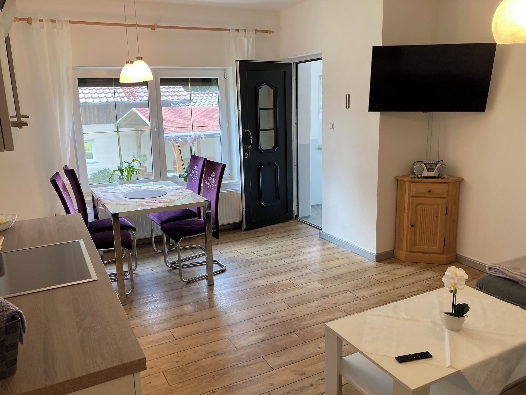 Un salon moderne comprenant un coin repas, un téléviseur fixé au mur et un meuble en bois.