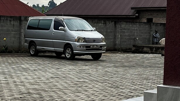A silver van parked on a cobblestone driveway with a brick building in the background.