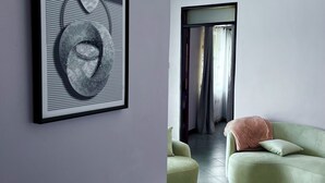 A modern living room with a green sofa, a patterned rug, and a framed abstract artwork on the wall.