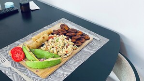 A table with a meal consisting of tortillas, scrambled eggs, and plantains, accompanied by sliced avocado and tomato.
