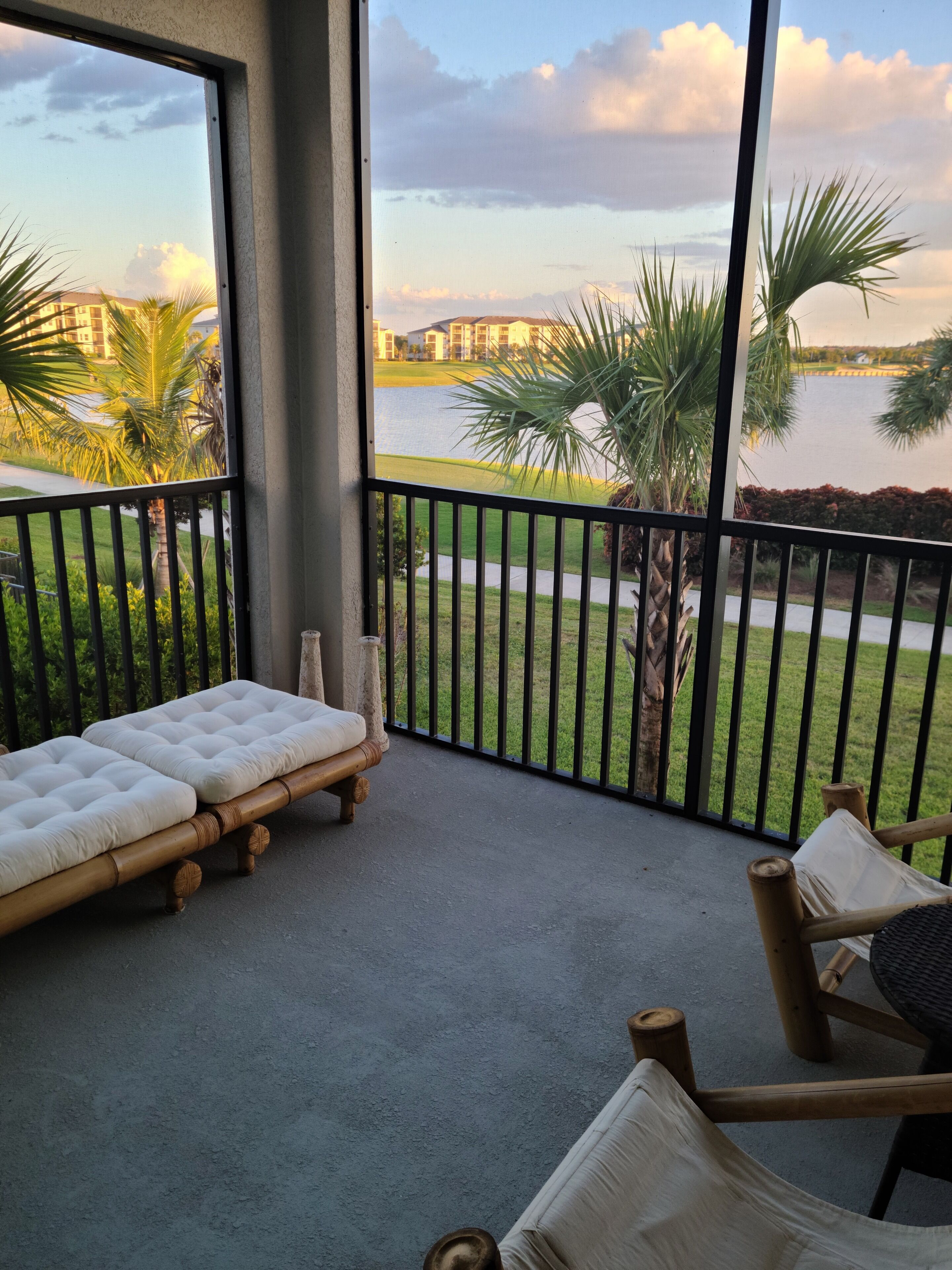 Ein Balkon mit Blick auf einen Golfplatz und ein Gewässer. Zwei Liegestühle und eine gepolsterte Bank sind vorhanden.
