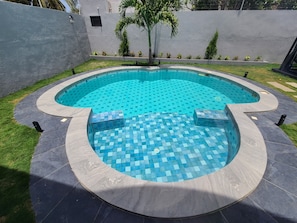 A circular swimming pool with a tiled edge and a surrounding deck.