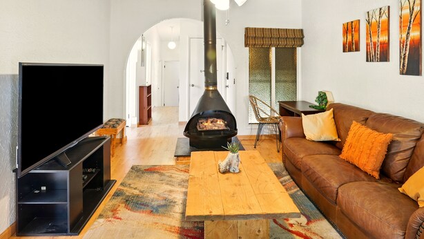 A living room with a fireplace, a television, a sofa, and a ceiling fan. - Cozy 2BR Ogden Condo - Pool, Trails, Snowbasin (Ogden)