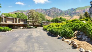 A hotel with multiple units, a paved driveway, and a mountainous backdrop. - Cozy 2BR Ogden Condo - Pool, Trails, Snowbasin (Ogden)