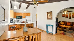 A modern kitchen with wooden cabinets, a dining table with chairs, and a ceiling fan. - Cozy 2BR Ogden Condo - Pool, Trails, Snowbasin (Ogden)