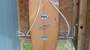 A surfboard with stickers, mounted on a wooden structure.