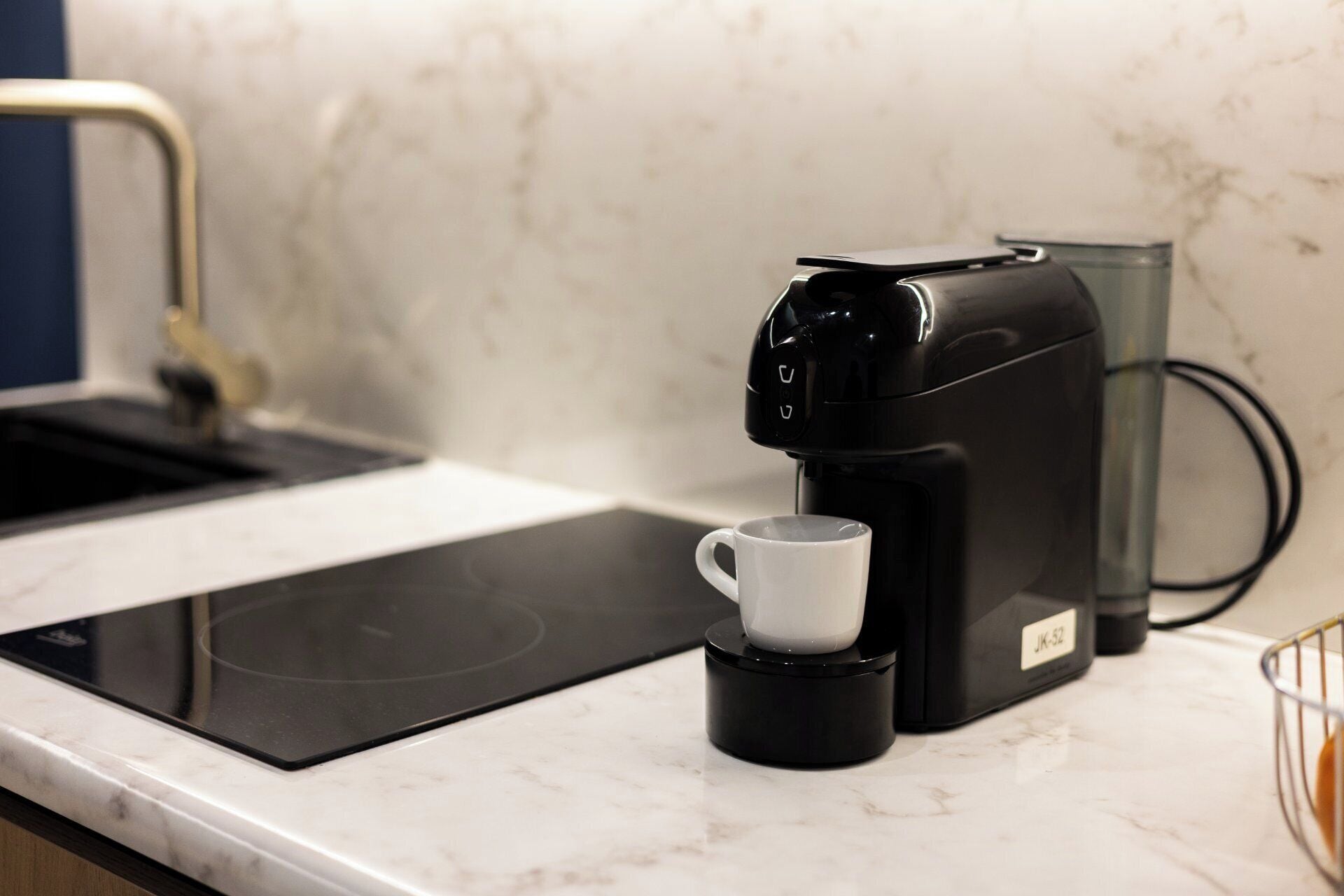 A coffee maker with a cup on a kitchen counter.