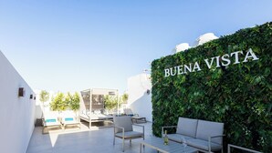 A rooftop patio with a white wall, a green wall with 'BUENA VISTA' text, and outdoor seating. - Buena Vista Suites (Sliema)