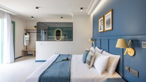 A modern bedroom with a large bed, a bathroom with a glass shower, and a view of the city. - Buena Vista Suites (Sliema)
