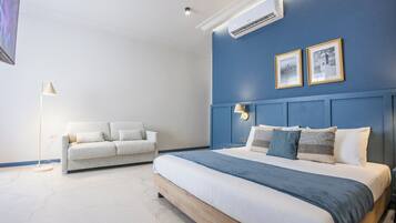 A bedroom with a bed, a sofa, and an air conditioning unit on the wall.