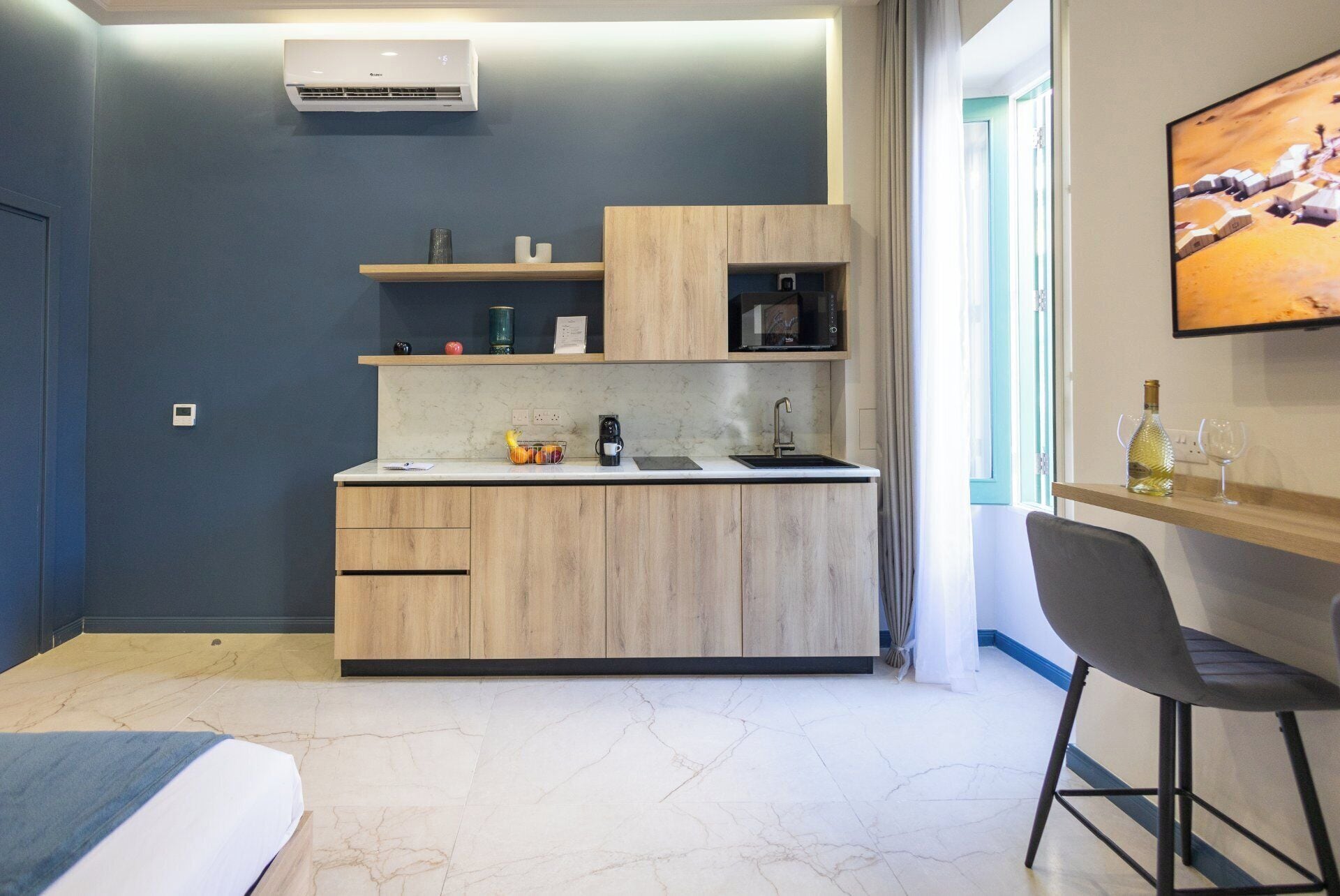 A compact kitchen with a built-in microwave, a coffee maker, and a fruit bowl.
