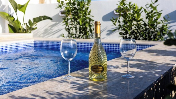 A poolside setting with a bottle of wine and two glasses. - Buena Vista Suites (Sliema)