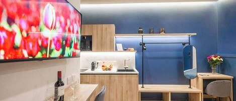 A modern kitchen with a TV, wooden cabinets, a sink, and a dining area with a table and chairs.