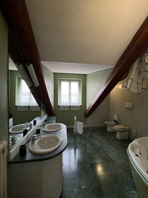 A bathroom with two sinks, a toilet, and a bathtub. There are windows with white curtains and a wooden ceiling. - BELVEDERE PALAZZO MADAMA (Torino)
