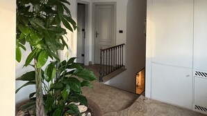 Un couloir avec une plante en pot, un escalier et une armoire.