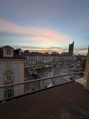 A cityscape with historic buildings and a busy intersection during sunset. - BELVEDERE PALAZZO MADAMA (Torino)
