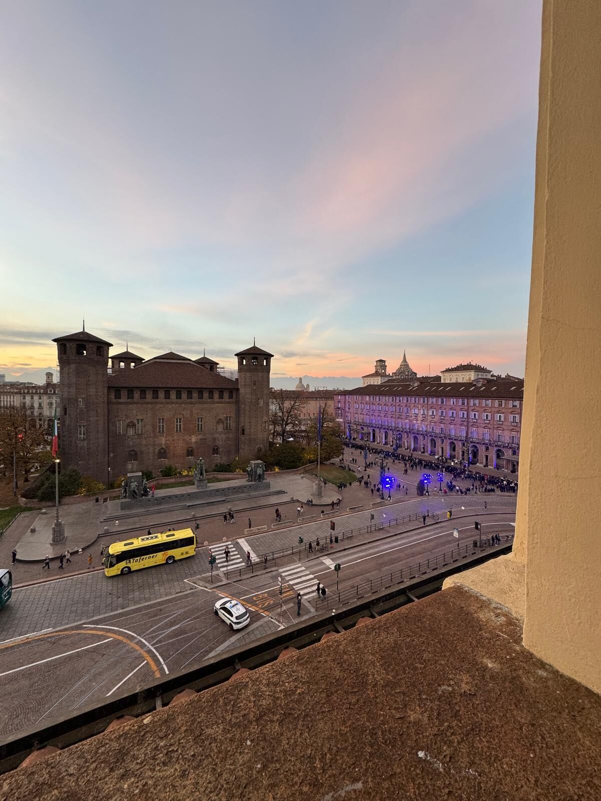 A city square with a historic building, a bus, and a car.